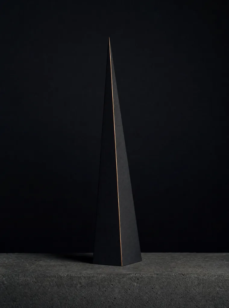 Der Keil frontal auf einer Betonkante, kühles Licht, tiefe schwarze Wand